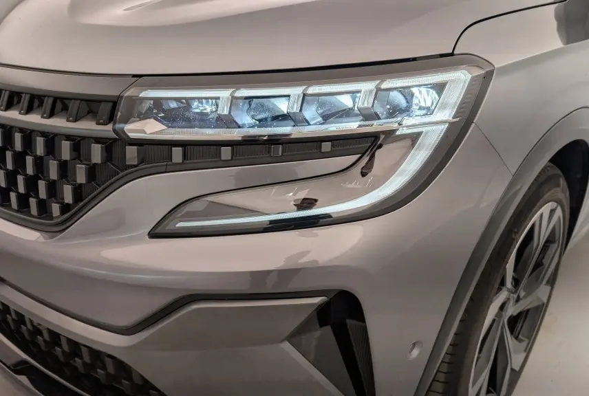 Gros plan sur l'avant droit gris schiste du Renault Espace E-Tech avec calandre à damiers et feux LED distinctifs.