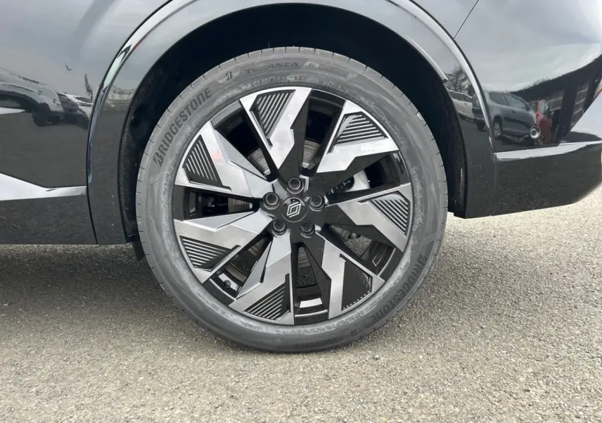 Gros plan sur la roue arrière droite noire d'une Renault Rafale esprit Alpine avec jante au design géométrique bicolore.