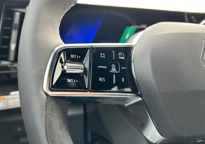 Gros plan sur les commandes gauche du volant noir du Renault Rafale esprit Alpine hybride 2025, avec boutons multifonctions.