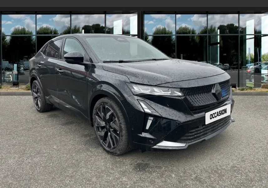 Renault Rafale noir en 3/4 avant droit, avec calandre noire et jantes noires, stationné devant un bâtiment vitré.