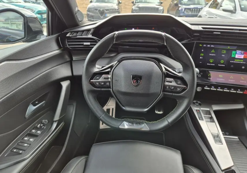 Vue intérieure frontale du volant cuir noir avec logo Peugeot et cockpit numérique lumineux du 408 Hybrid 2024.