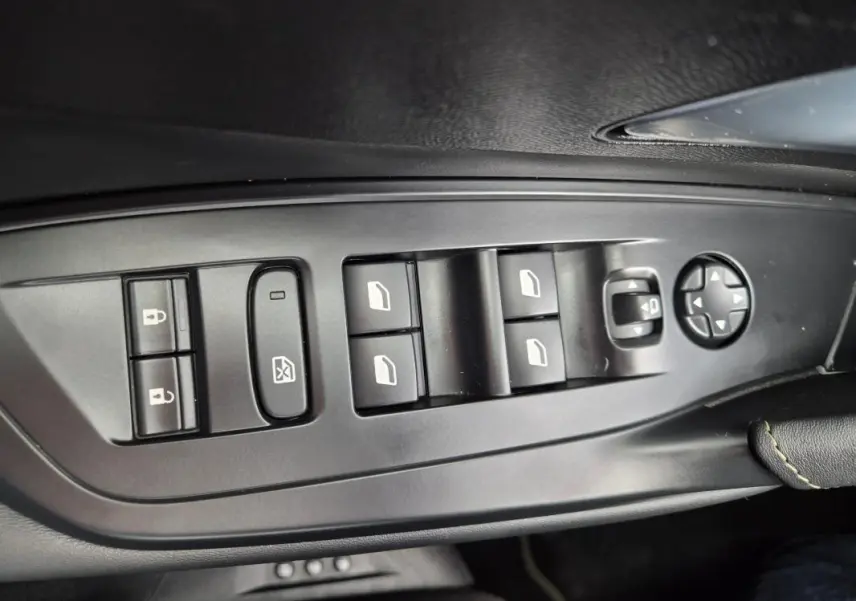 Vue rapprochée des commandes de lève-vitres et rétroviseurs côté conducteur d’une Peugeot 408 Hybrid 136 e-DCS6 GT noire.