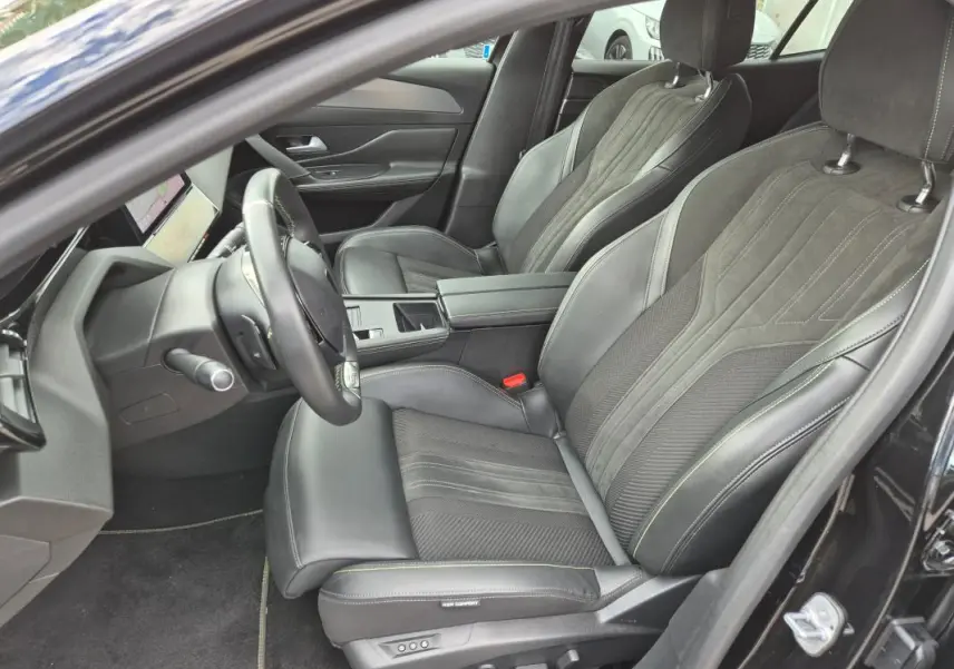 Vue intérieure côté conducteur de la Peugeot 408 Hybrid GT 2024 noire, sièges cuir et alcantara avec accoudoir central.