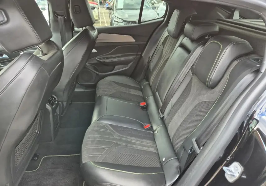 Vue intérieure côté droit des sièges arrière en cuir noir avec surpiqûres vertes du Peugeot 408 Hybrid 2024.