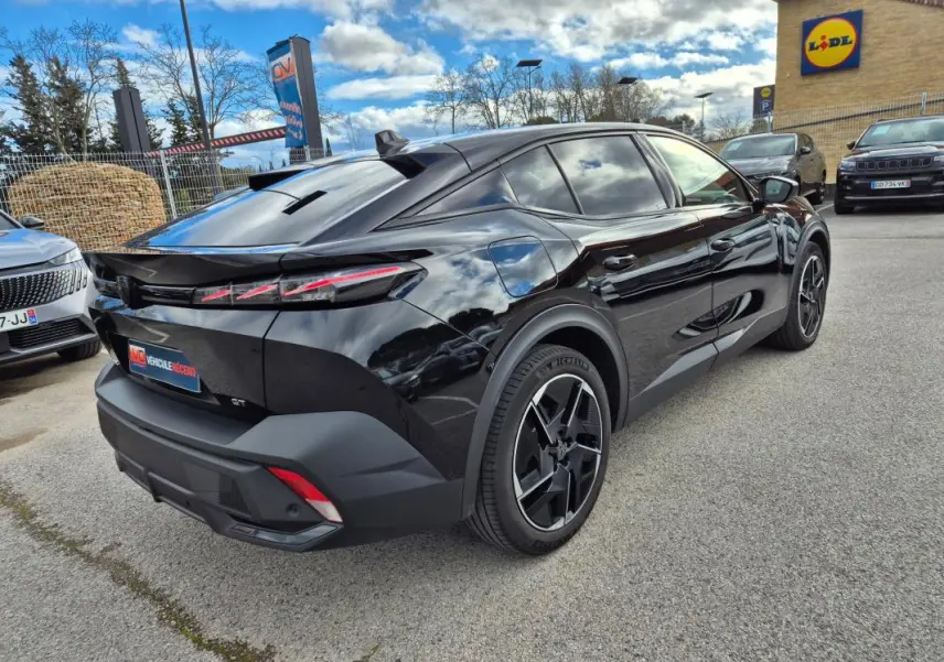 Vue 3/4 arrière droite d'une Peugeot 408 Hybrid GT noire 2024 avec jantes alliage 19 pouces et feux arrière LED distinctifs.