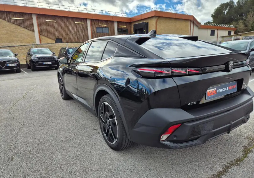 Vue 3/4 arrière droite d'une Peugeot 408 Hybrid 136 e-DCS6 GT noire avec jantes alliage 19 pouces et feux arrière LED distinctifs.
