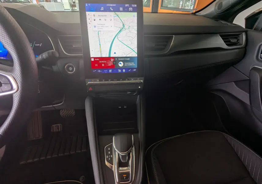 Vue intérieure centrée sur la console centrale et l’écran tactile vertical du Renault Symbioz gris Cassiopée, avec levier de vitesse automatique.