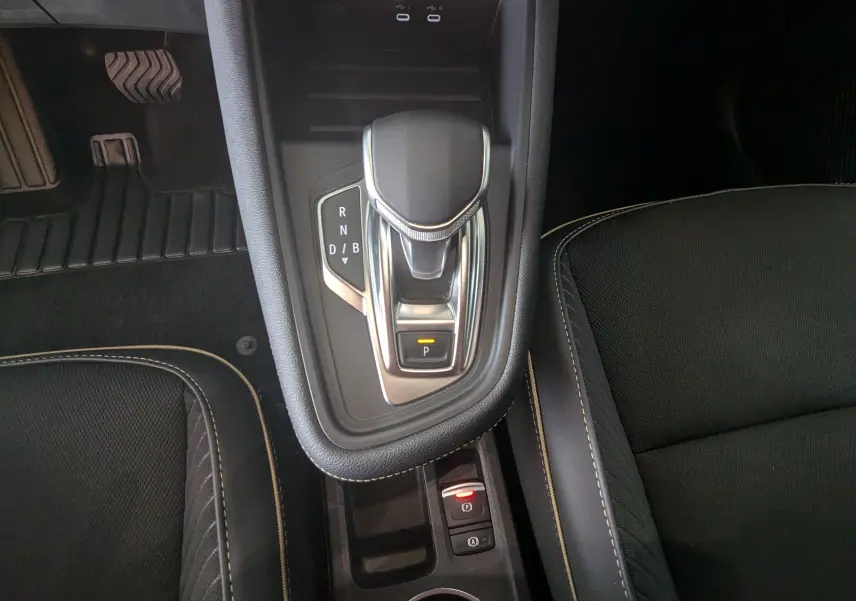 Vue plongeante sur la console centrale de la Renault Symbioz E-Tech Full Hybrid 145 Iconic avec levier de vitesse et sièges noirs.