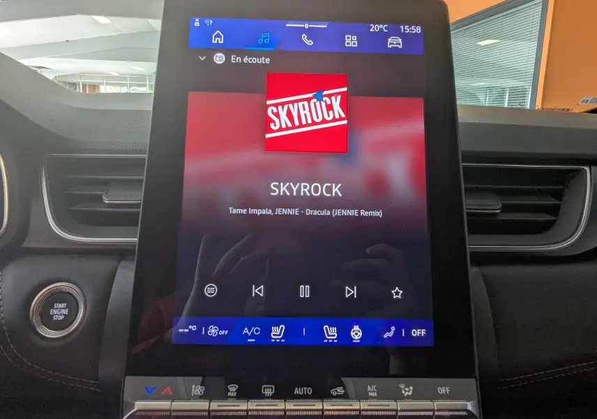Écran tactile central de la Renault Symbioz gris cassiopée affichant la radio Skyrock et commandes climatisation en intérieur.