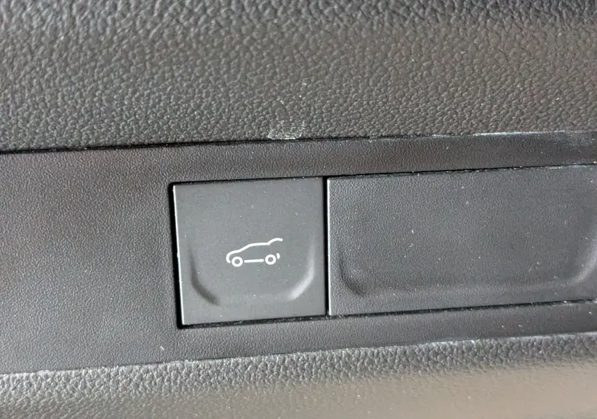 Bouton noir intérieur avec pictogramme blanc d'ouverture du coffre sur Renault Symbioz E-Tech gris Cassiopée.