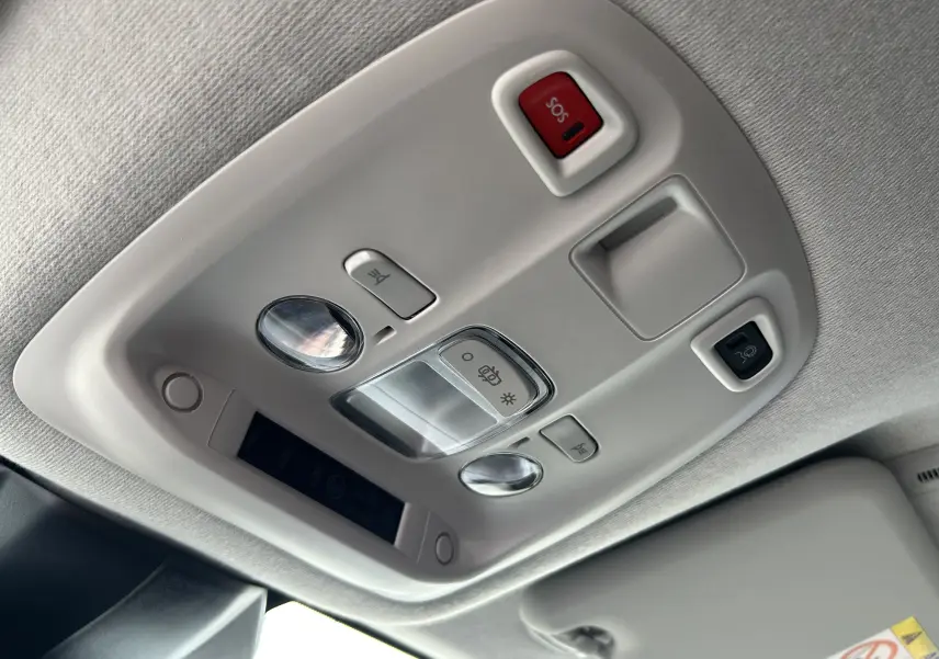 Vue en contre-plongée du plafonnier intérieur gris clair du Citroën Jumpy Fourgon 2025 avec bouton SOS rouge et éclairages intégrés.