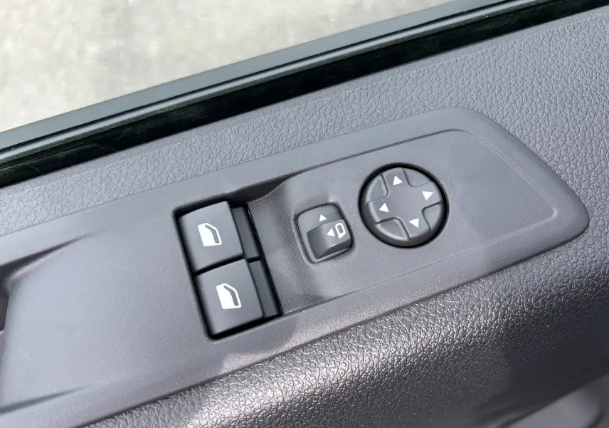 Gros plan sur les commandes de réglage des vitres et des rétroviseurs du côté conducteur d'un Citroën Jumpy Fourgon gris acier.