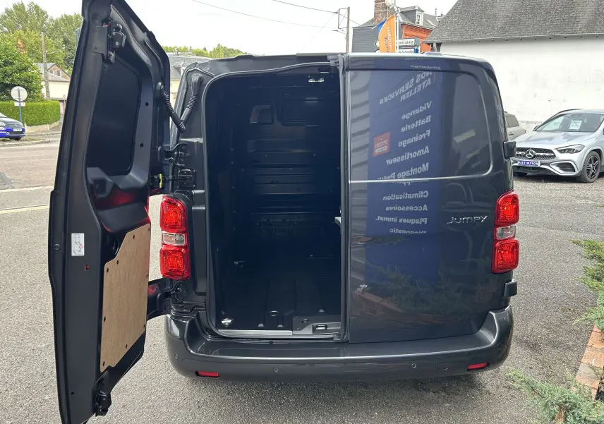 Vue arrière du Citroën Jumpy Fourgon gris acier 2025 avec porte gauche ouverte dévoilant l'espace de chargement vide.