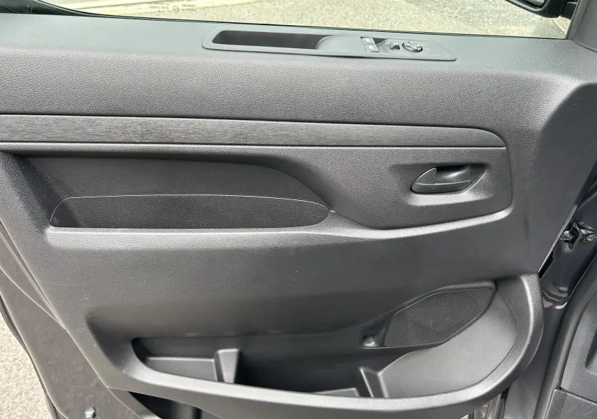 Vue rapprochée de la porte côté gauche du Citroën Jumpy Fourgon gris acier, avec poignée et commandes de vitres.