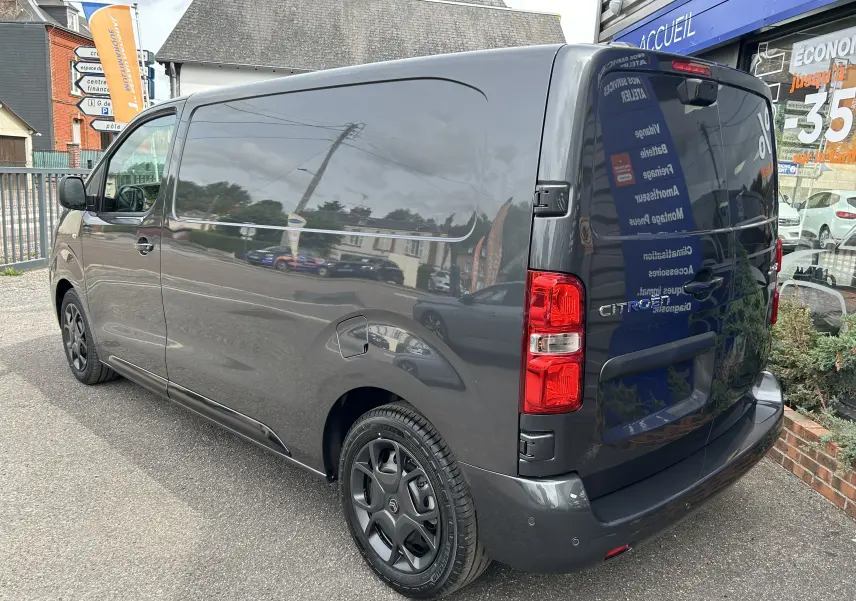 Vue 3/4 arrière droite du Citroën Jumpy Fourgon gris acier, mettant en valeur ses feux arrière et jantes noires.