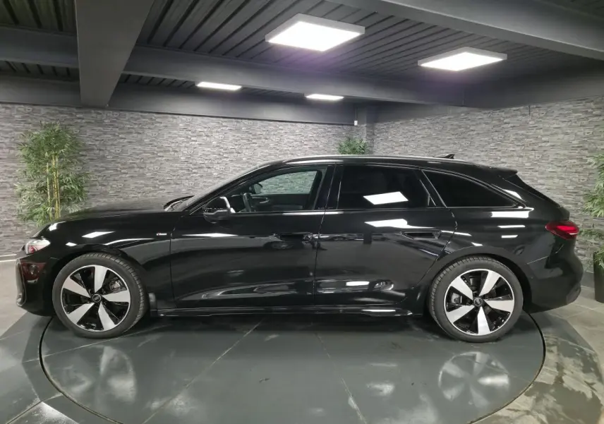Audi A5 Avant noire vue de profil côté gauche dans un showroom avec jantes 5 branches doubles brillantes.