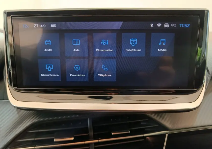 Écran tactile central affichant les menus multimédia et climatisation dans le Peugeot 208 gris clair 2025.