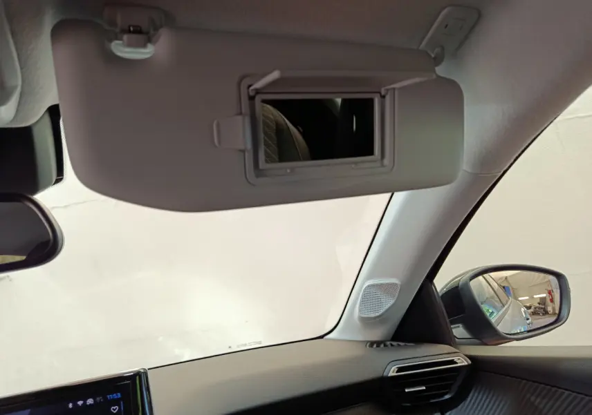Intérieur de la Peugeot 208 gris clair, vue sur pare-soleil avec miroir, tableau de bord et rétroviseur côté droit.