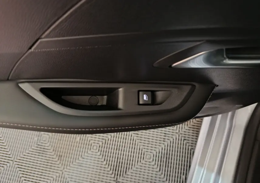Poignée intérieure côté gauche de la porte gris clair du Peugeot 208 PureTech 100 S&S Allure avec bouton de verrouillage.