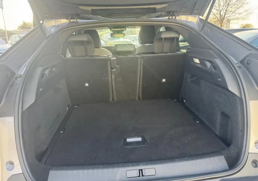 Coffre ouvert vu de l’arrière d’un Peugeot 3008 gris 2025, montrant l’espace de chargement et les sièges arrière rabattus.