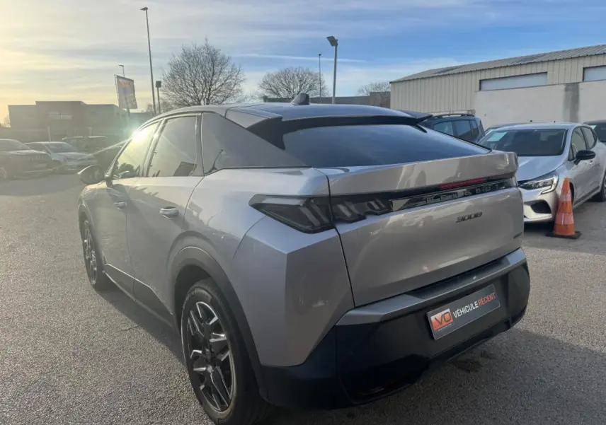 Vue 3/4 arrière droite d’un Peugeot 3008 Hybrid gris 2025 avec jantes alliage noires de 19 pouces et vitres teintées.