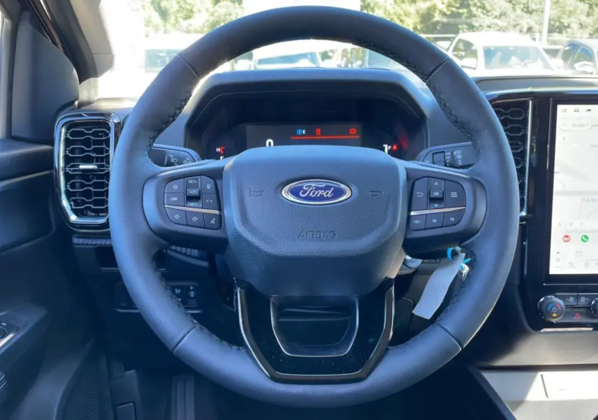 Vue rapprochée du volant cuir multifonctions noir du Ford Ranger 2025 avec tableau de bord numérique et écran tactile GPS.