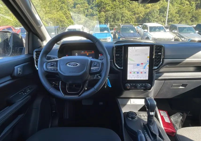 Vue intérieure avant du Ford Ranger 2025 noir shadow, volant cuir multifonctions et écran tactile vertical avec navigation GPS.