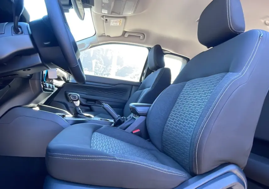 Vue intérieure côté conducteur du Ford Ranger 2025, sièges tissu gris avec surpiqûres blanches et console centrale visible.