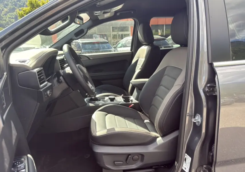 Vue intérieure côté conducteur du Volkswagen Amarok Simple Cabine 2026 gris foncé, avec sièges cuir et tableau de bord moderne.