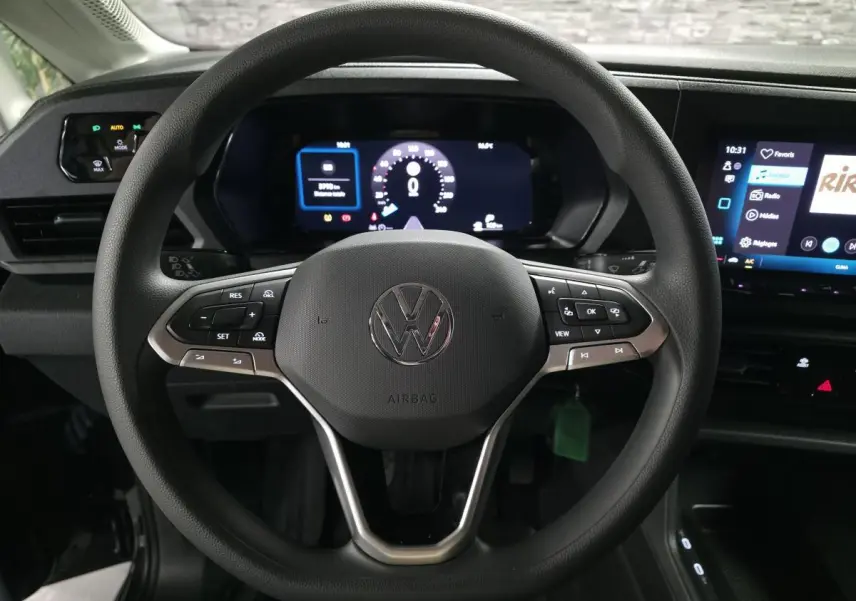 Vue rapprochée du volant noir multifonction du Volkswagen Caddy 2024 avec tableau de bord digital et écran tactile.