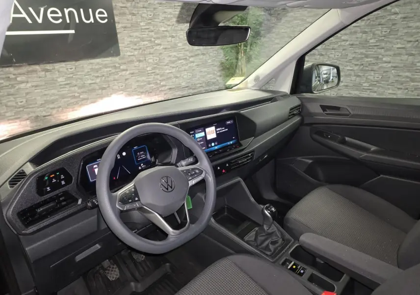 Vue intérieure côté conducteur du Volkswagen Caddy 2024 noir, avec tableau de bord digital et volant multifonction.