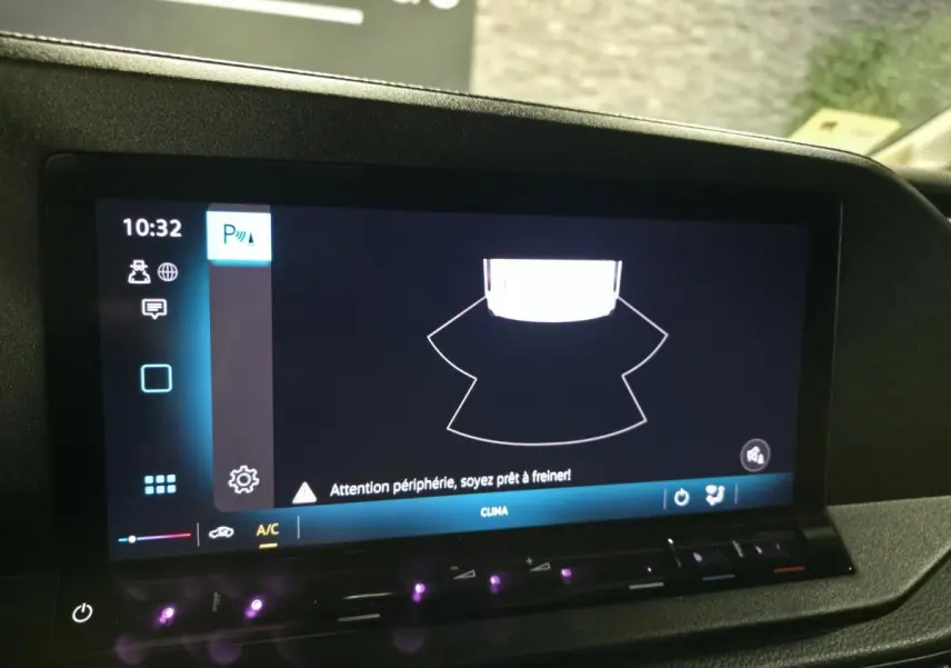 Écran tactile intérieur du Volkswagen Caddy Cargo noir 2024 montrant l'alerte de détection périphérique au stationnement.