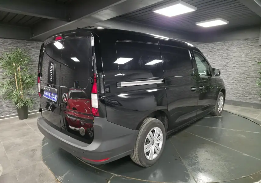 Vue 3/4 arrière droite d’un Volkswagen Caddy Cargo noir métallisé avec portes arrière battantes dans un showroom.