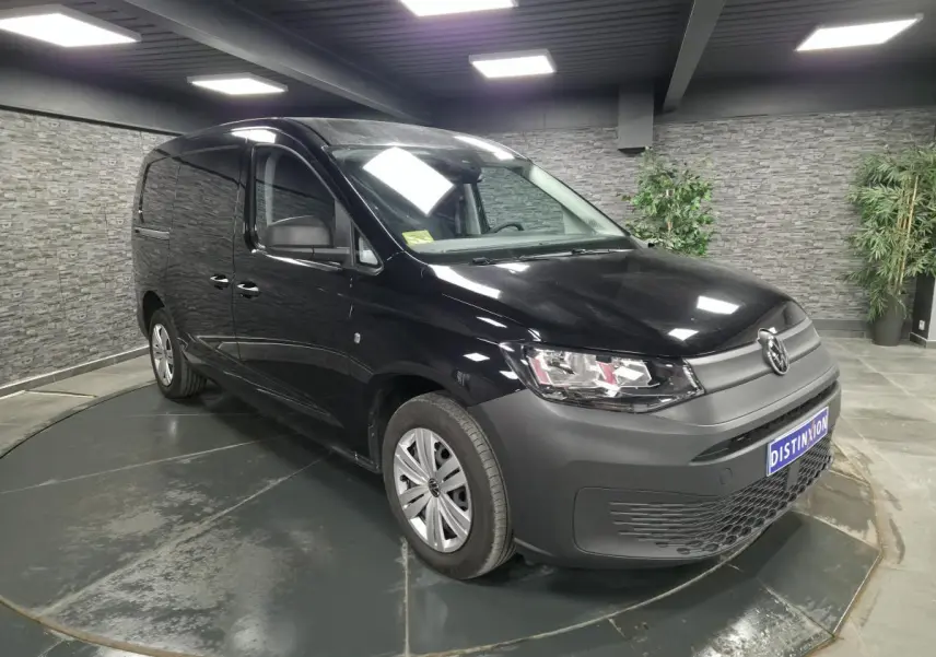 Volkswagen Caddy Cargo noir vue 3/4 avant droit en intérieur avec pare-chocs et jantes noires.
