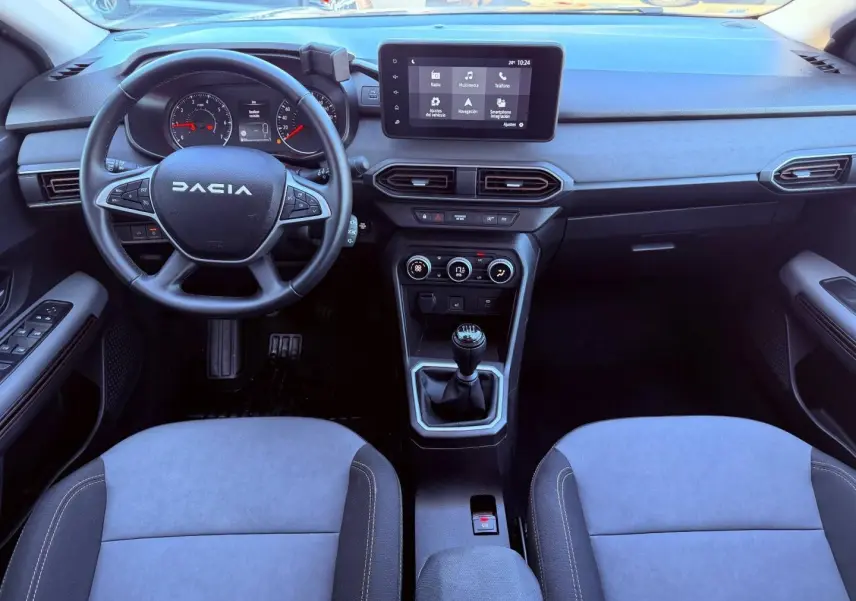 Vue intérieure avant du tableau de bord et volant noir de la Dacia Sandero 2025 avec écran tactile et boîte manuelle.