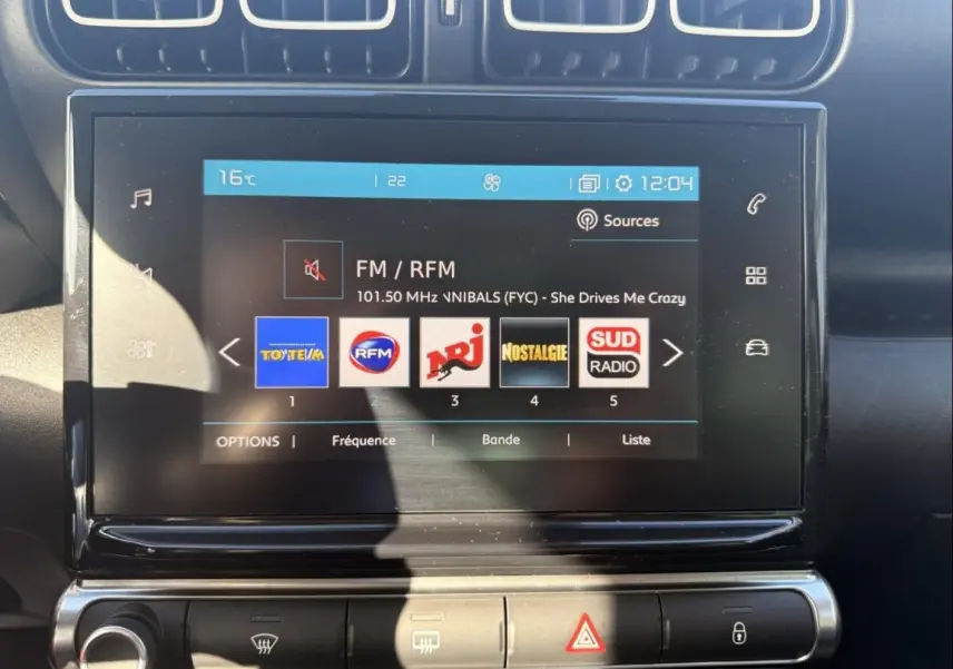 Écran tactile central du Citroën C3 Aircross gris métal 2021, affichant les stations radio FM avec commandes climatisation en dessous.