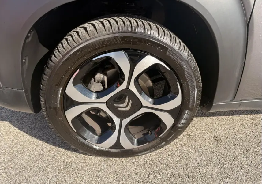 Gros plan sur la roue avant droite du Citroën C3 Aircross gris métal, avec jante alliage noire et argentée distinctive.
