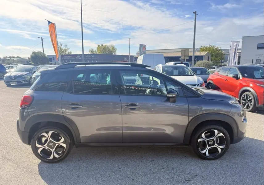 Vue de profil côté gauche d’un Citroën C3 Aircross gris métal 2021 avec jantes distinctives et toit noir.
