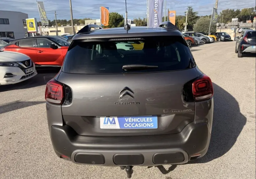 Vue arrière d’un Citroën C3 Aircross gris métal 2021 avec feux arrière carrés et attelage visible sur parking.