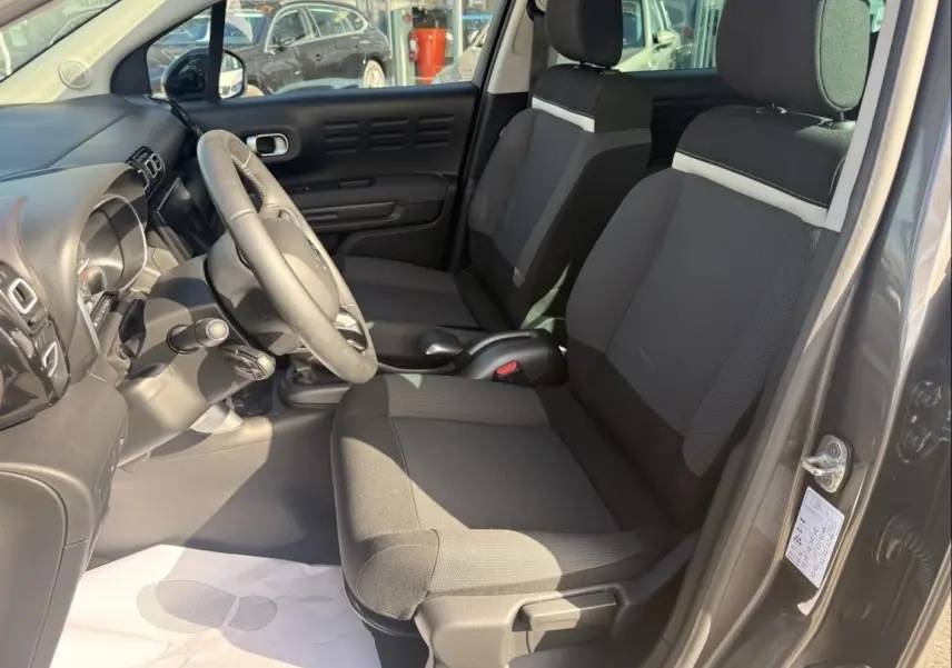 Vue intérieure côté conducteur du Citroën C3 Aircross gris métal 2021, sièges tissu bicolore et volant multifonction.