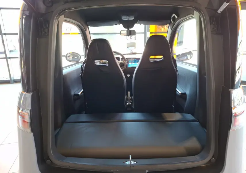 Vue arrière ouverte du SIMPLICI S1 gris perle avec toit noir, montrant les sièges avant et l'intérieur compact électrique.