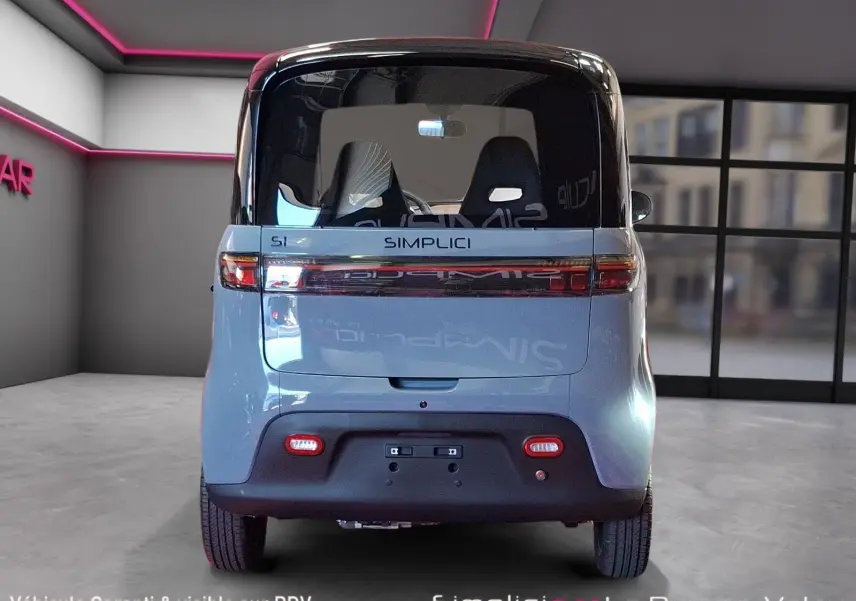 Vue arrière du Simplici S1 2025 gris perle avec toit noir, feux horizontaux et pare-chocs noir mat dans un showroom.