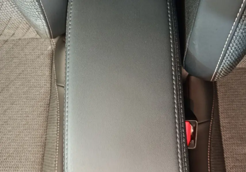 Accoudoir central avant en cuir gris foncé entre les sièges tissu de la Peugeot 208 PureTech 100 S&S Allure 2025.