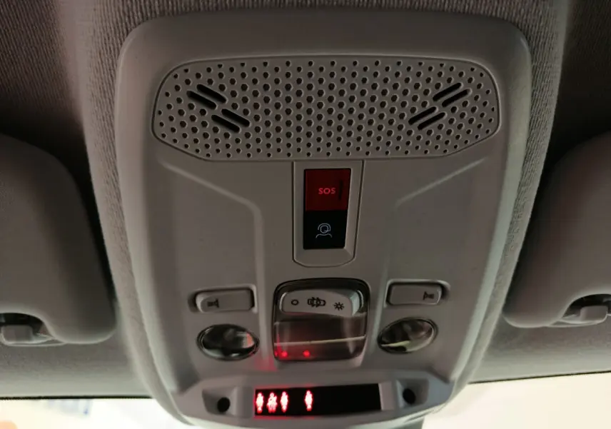 Gros plan sur le plafonnier intérieur gris clair avec bouton SOS rouge et commandes d'éclairage de la Peugeot 208 2025.