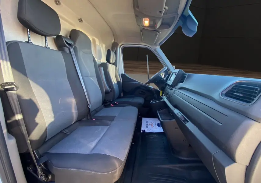 Vue intérieure côté droit du poste de conduite du Nissan Interstar 2022 avec sièges tissu gris et tableau de bord noir.