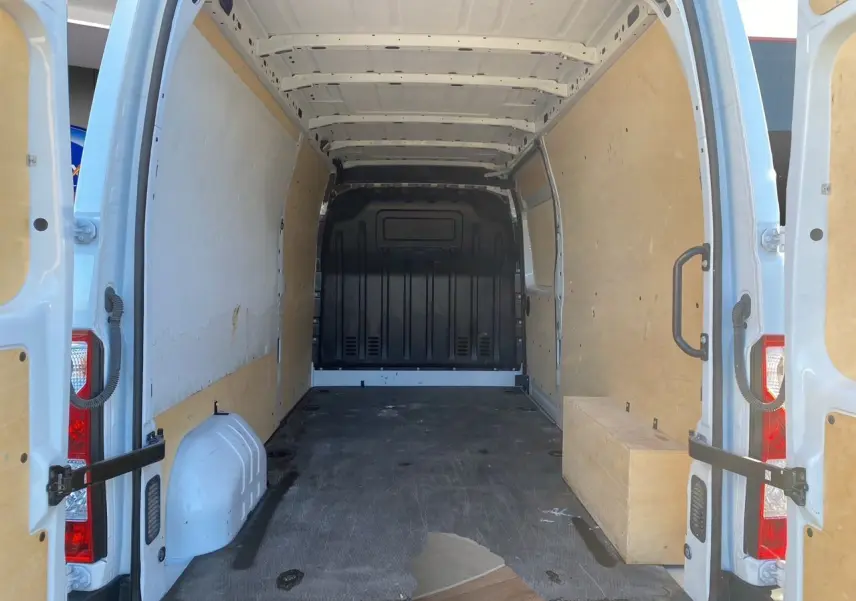 Vue arrière intérieure du fourgon blanc Nissan Interstar L3H2 2022, montrant l'espace de chargement avec parois en bois.