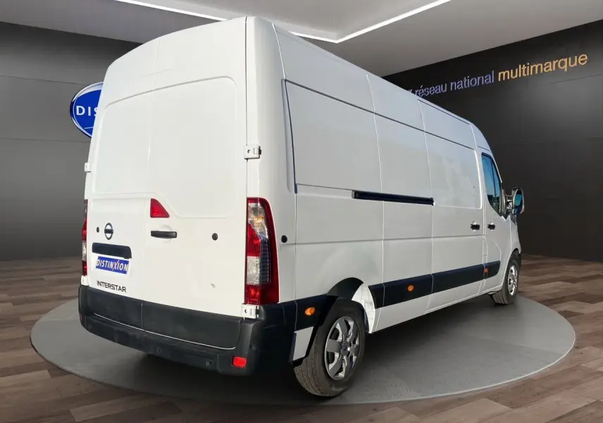 Vue 3/4 arrière droite d’un utilitaire Nissan Interstar blanc, avec caméra de recul et antibrouillards visibles.