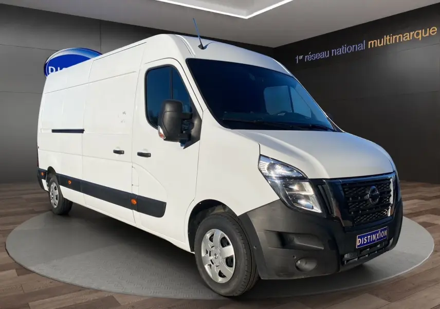 Nissan Interstar blanc en vue 3/4 avant droit, avec pare-chocs noir et rétroviseurs noirs, stationné en intérieur.