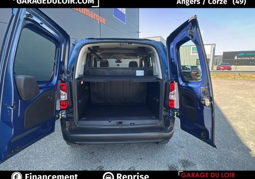 Vue arrière du Peugeot Rifter bleu 2024 avec portes ouvertes montrant le coffre spacieux et la grille de séparation intérieure.