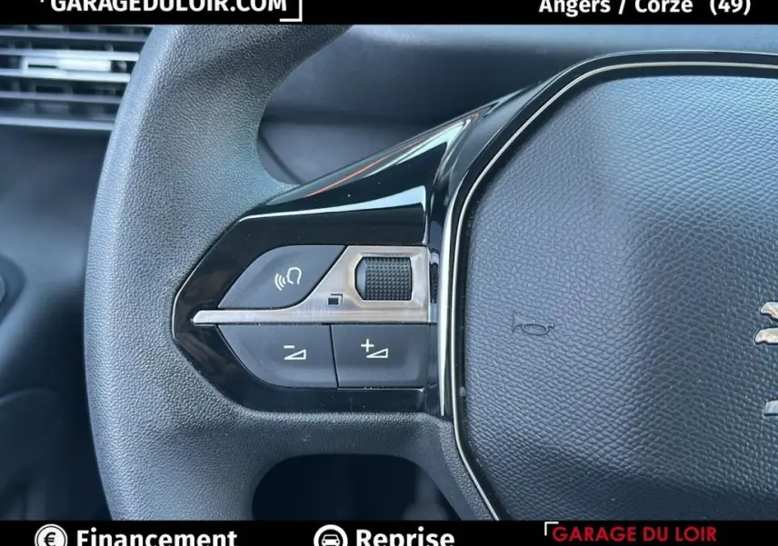 Gros plan sur les commandes gauche du volant noir texturé du Peugeot Rifter 2024, avec boutons de volume et fonction vocale.